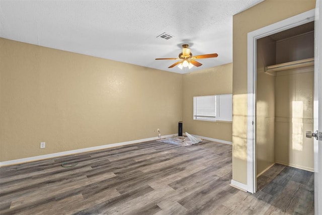 unfurnished bedroom featuring a ceiling fan, baseboards, dark wood-style floors, visible vents, and a textured ceiling