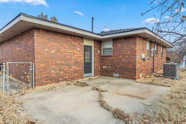 back of house featuring brick siding, central air condition unit, a patio area, and fence