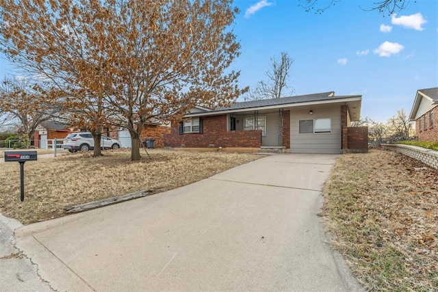 single story home featuring concrete driveway and brick siding