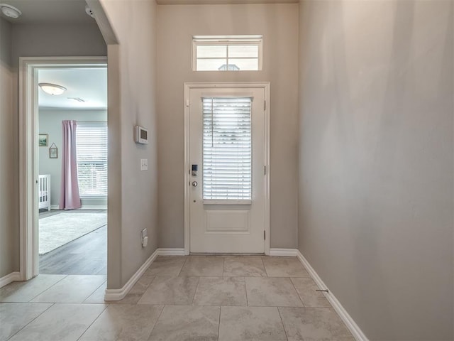 entryway featuring baseboards, arched walkways, and light tile patterned flooring