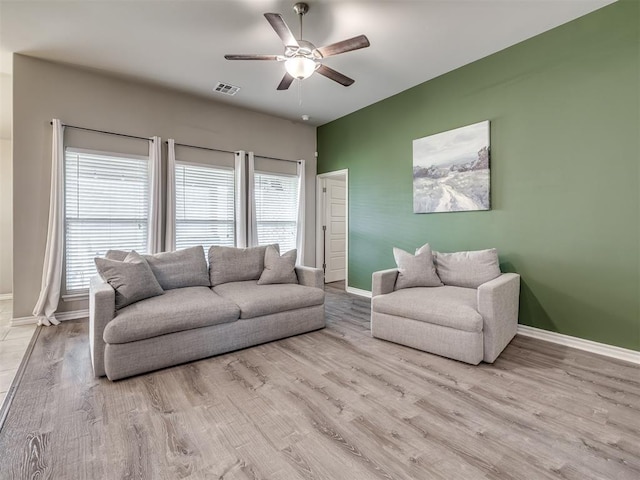 living area with baseboards, wood finished floors, visible vents, and ceiling fan