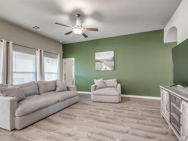 living room featuring visible vents, baseboards, light wood-style flooring, and a ceiling fan