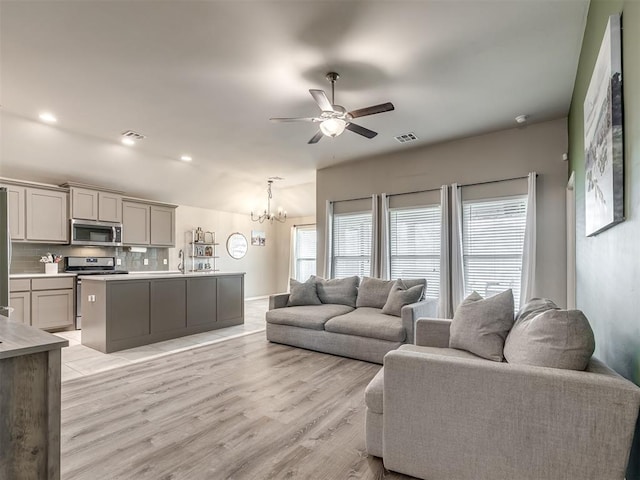 living area featuring visible vents, light wood finished floors, recessed lighting, vaulted ceiling, and ceiling fan with notable chandelier