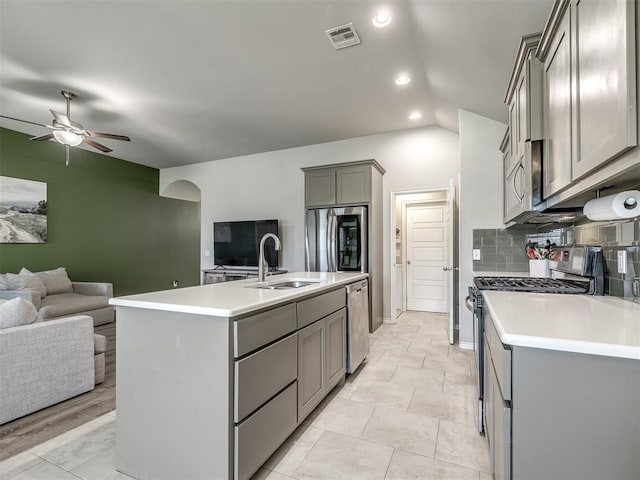 kitchen with visible vents, gray cabinetry, a sink, open floor plan, and appliances with stainless steel finishes