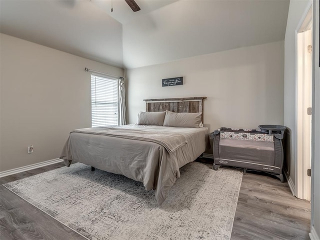 bedroom featuring a ceiling fan, lofted ceiling, wood finished floors, and baseboards