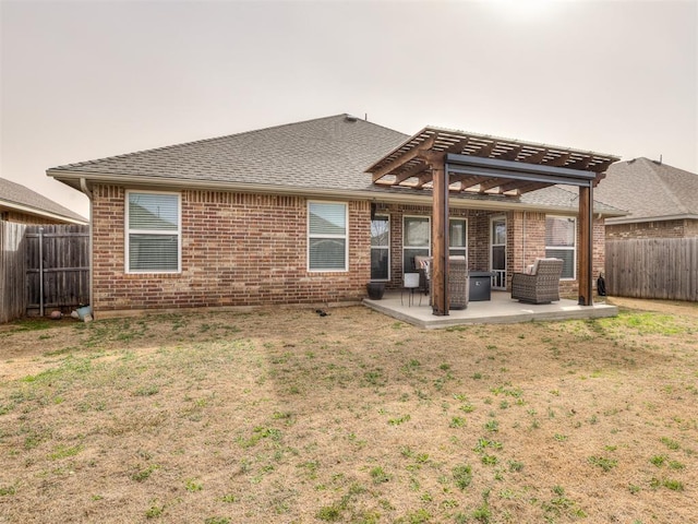 rear view of property featuring a lawn, a pergola, a fenced backyard, brick siding, and a patio area