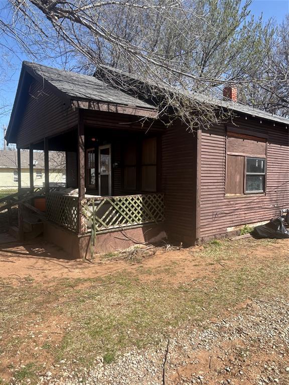 view of side of home featuring covered porch and a chimney