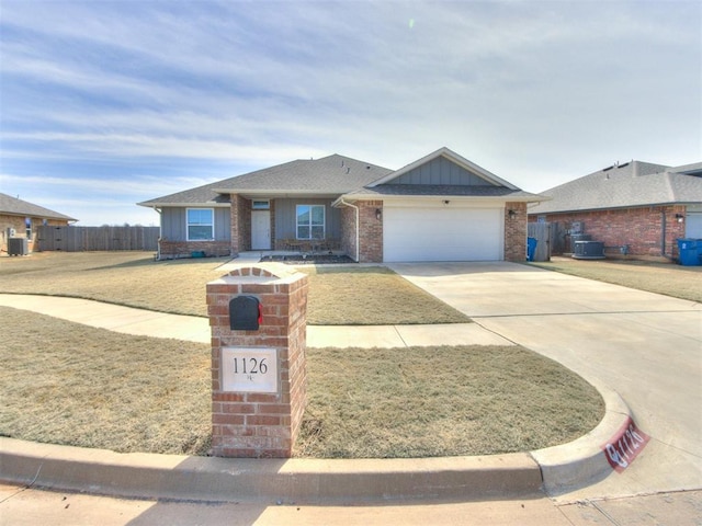 view of front of home featuring brick siding, fence, concrete driveway, cooling unit, and a garage