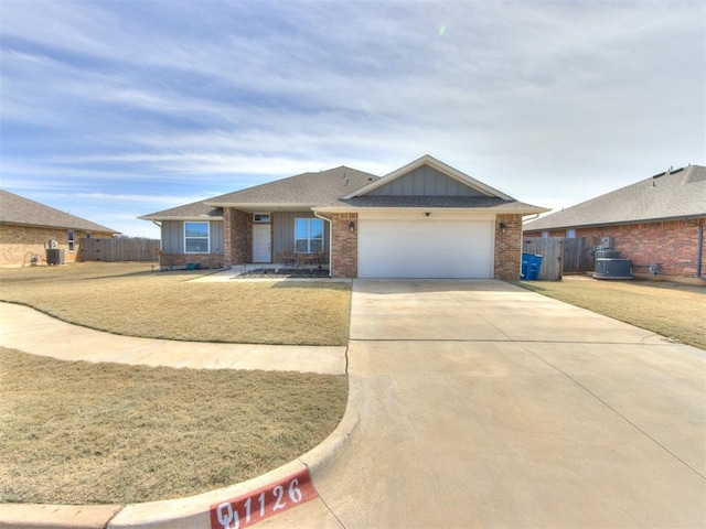 view of front of house featuring brick siding, driveway, a garage, and fence