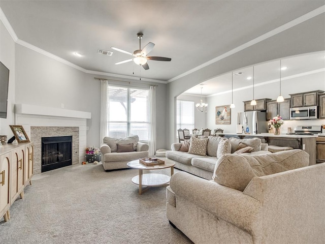 living area with visible vents, ornamental molding, light carpet, ceiling fan with notable chandelier, and a fireplace