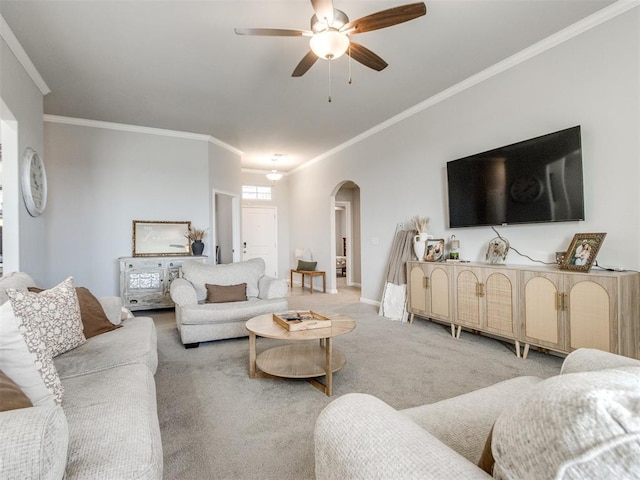 living area with crown molding, baseboards, light colored carpet, arched walkways, and a ceiling fan