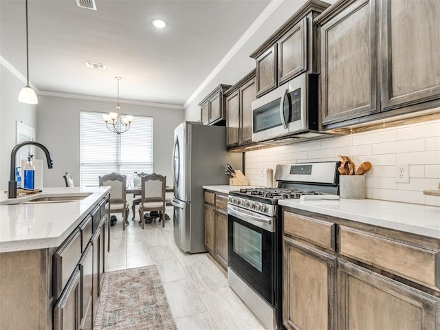 kitchen with visible vents, ornamental molding, a sink, appliances with stainless steel finishes, and an inviting chandelier