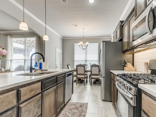 kitchen featuring visible vents, a sink, stainless steel appliances, a notable chandelier, and backsplash