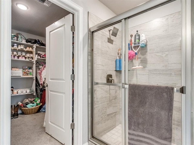 bathroom with a shower stall, a spacious closet, and visible vents