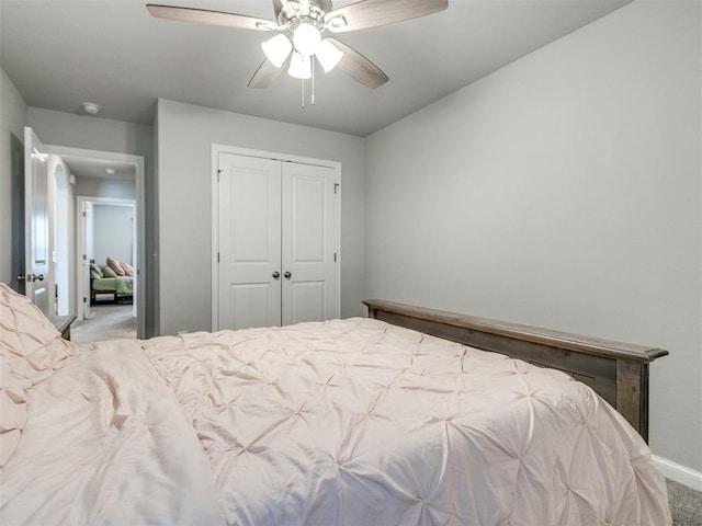 carpeted bedroom with a closet, baseboards, and ceiling fan