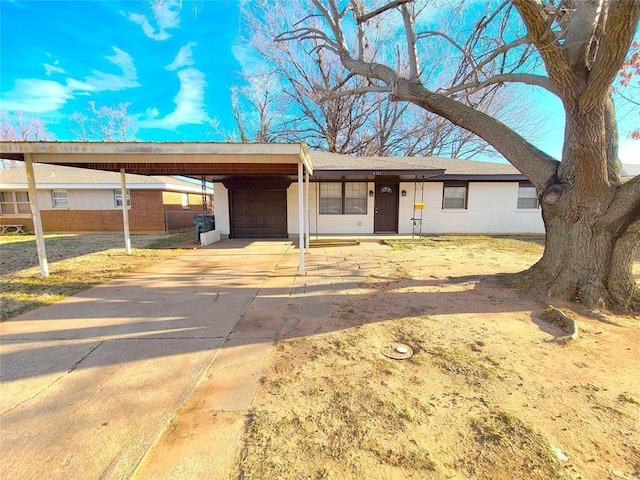 single story home featuring brick siding, an attached carport, an attached garage, and driveway