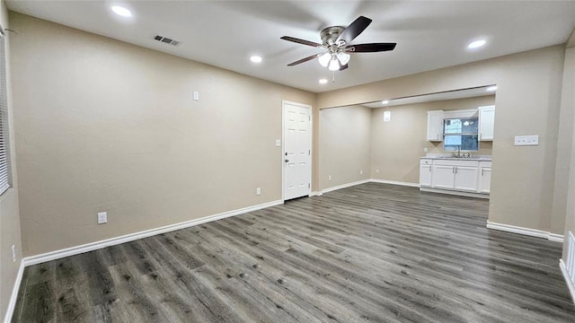 unfurnished living room with baseboards, dark wood-style floors, and a ceiling fan