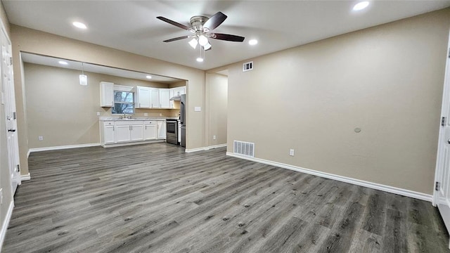 unfurnished living room with visible vents, baseboards, ceiling fan, wood finished floors, and a sink