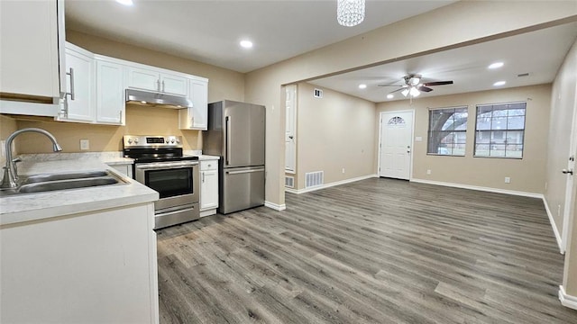 kitchen with a sink, under cabinet range hood, white cabinetry, appliances with stainless steel finishes, and light countertops