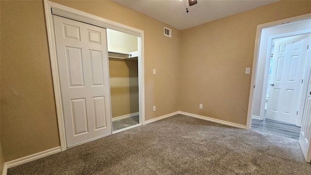 unfurnished bedroom featuring visible vents, dark carpet, a closet, baseboards, and ceiling fan