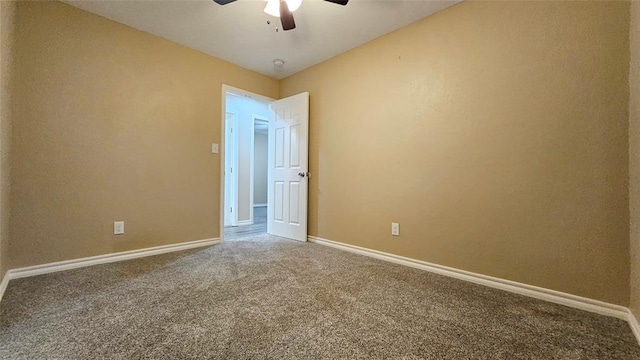 carpeted spare room with a ceiling fan and baseboards