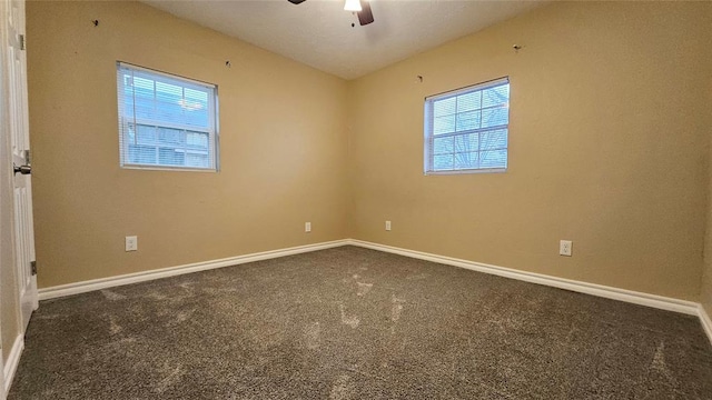 empty room featuring baseboards, ceiling fan, and dark carpet