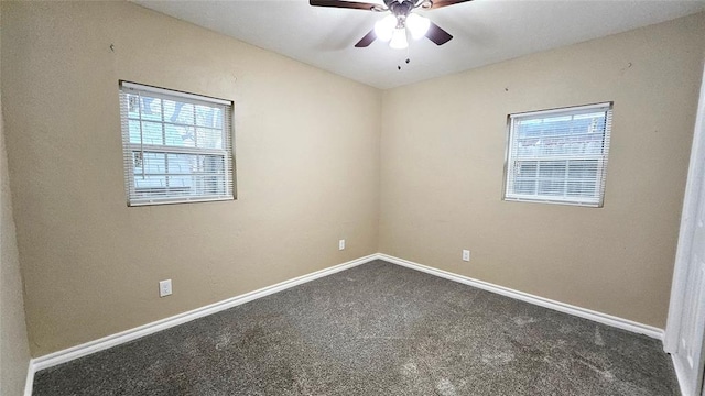 empty room with a wealth of natural light, baseboards, a ceiling fan, and dark carpet