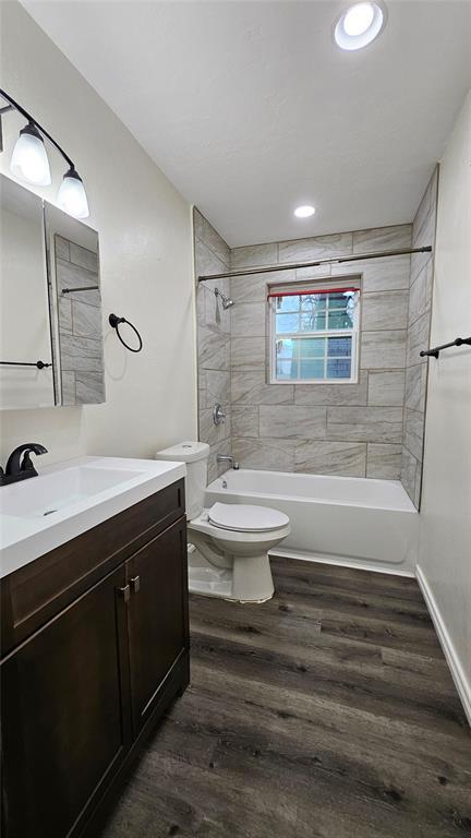 bathroom featuring vanity, toilet, shower / bath combination, and wood finished floors