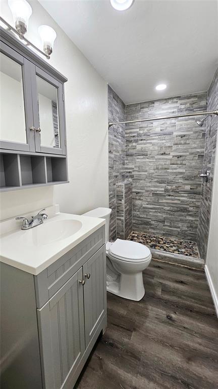 full bathroom with a stall shower, toilet, vanity, and wood finished floors