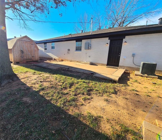 back of house featuring cooling unit, a patio, an outbuilding, and a shed