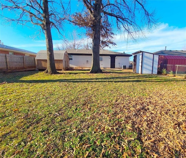 view of yard featuring an outdoor structure, a fenced backyard, and a shed