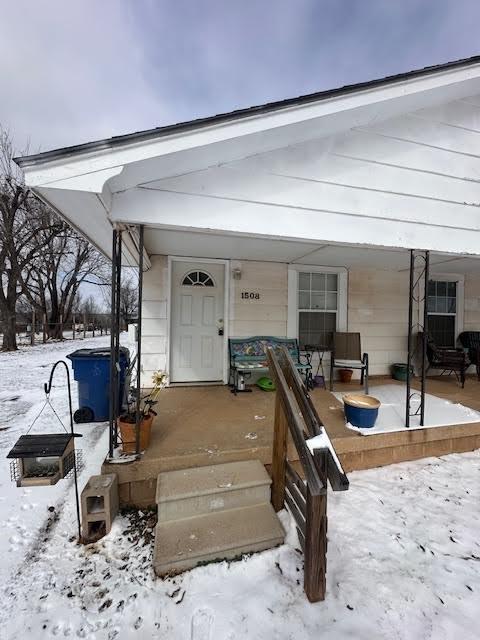 snow covered property entrance featuring a porch