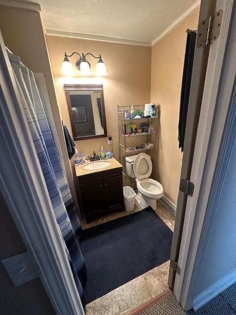 bathroom with toilet, vanity, baseboards, and ornamental molding