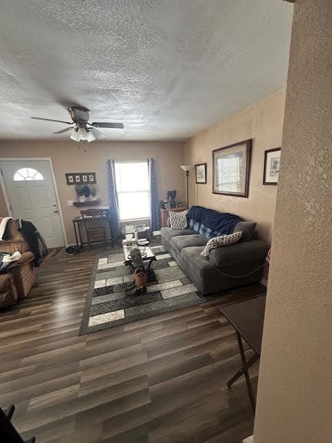 living area with a textured wall, a textured ceiling, a ceiling fan, and wood finished floors