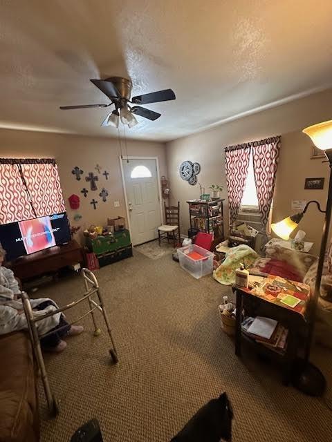living area featuring ceiling fan, carpet flooring, and plenty of natural light