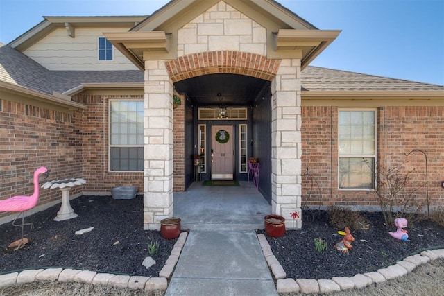 property entrance with stone siding, brick siding, and roof with shingles