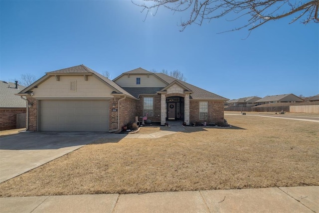 view of front facade featuring brick siding, driveway, a front yard, and a garage