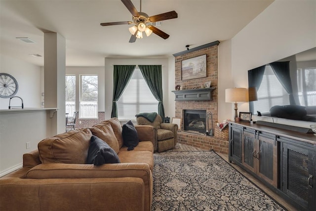 living room featuring a ceiling fan, a fireplace, visible vents, and baseboards