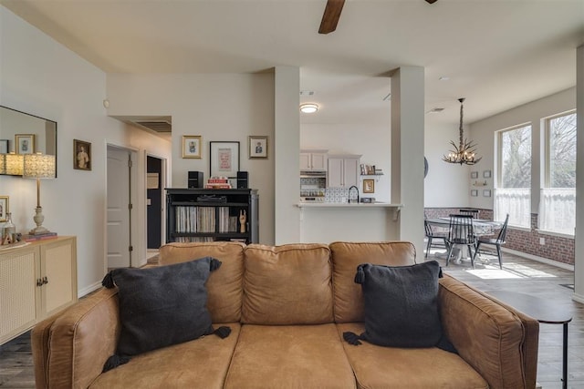 living area with ceiling fan with notable chandelier, visible vents, and baseboards