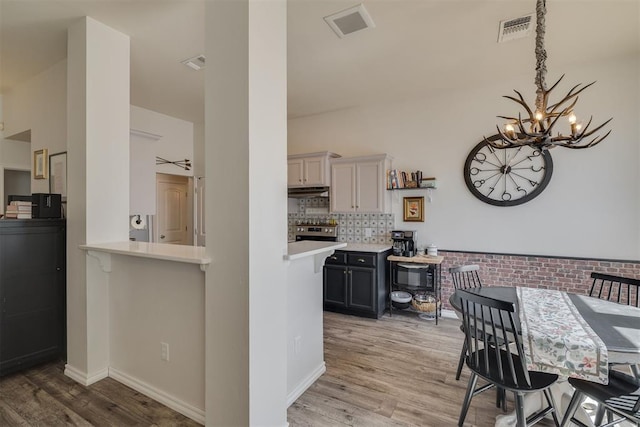 kitchen with light countertops, a notable chandelier, visible vents, and light wood finished floors