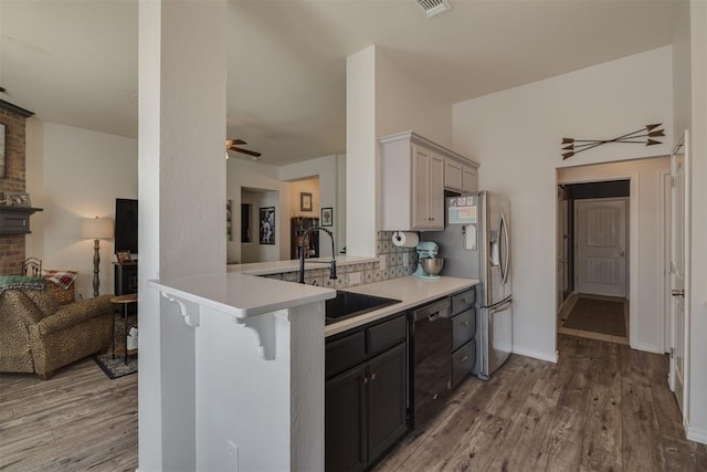 kitchen with a sink, light wood-type flooring, black dishwasher, and light countertops