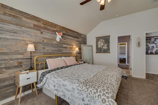 carpeted bedroom with an accent wall, vaulted ceiling, a ceiling fan, and wood walls