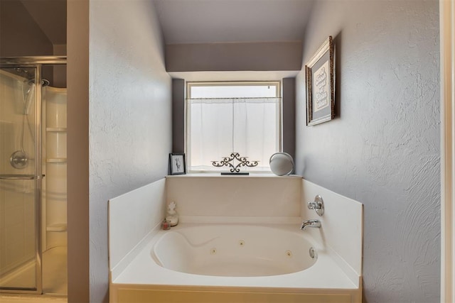 full bathroom with a tub with jets, a stall shower, and a textured wall