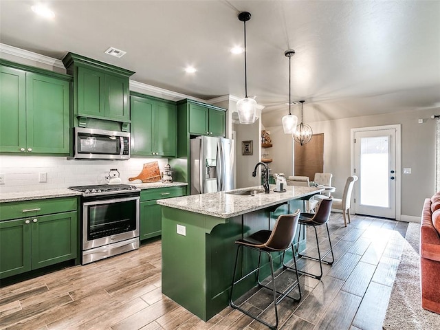 kitchen with a sink, stainless steel appliances, decorative backsplash, and green cabinetry