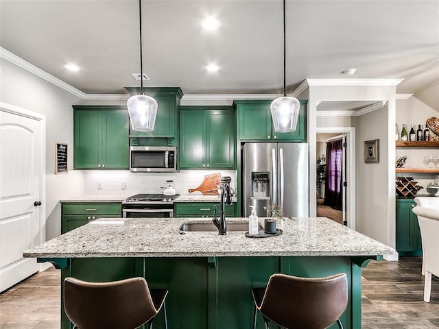 kitchen featuring green cabinetry, stainless steel appliances, a kitchen bar, and light stone countertops