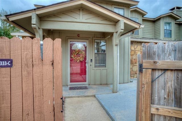 entrance to property with stone siding, board and batten siding, and fence