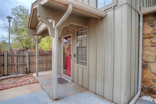 property entrance with board and batten siding and fence