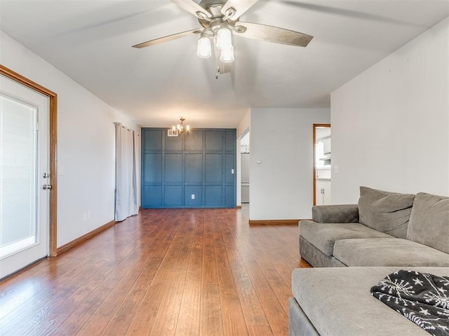 living room with baseboards, wood-type flooring, plenty of natural light, and ceiling fan with notable chandelier