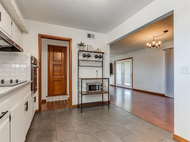 kitchen with visible vents, backsplash, light wood-style flooring, stainless steel appliances, and white cabinetry