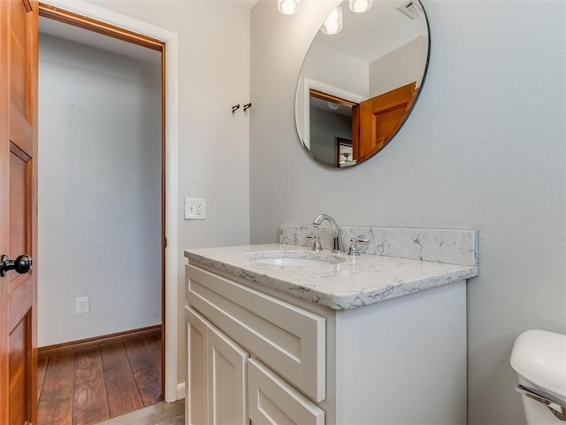 bathroom with visible vents, toilet, hardwood / wood-style floors, baseboards, and vanity